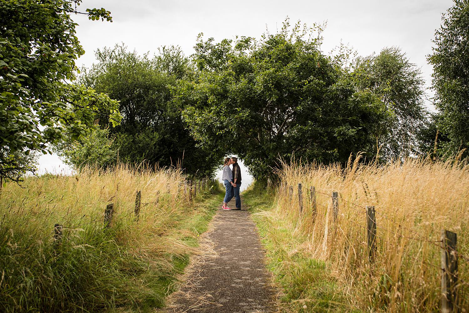 a couple face each other and kiss on a path outside