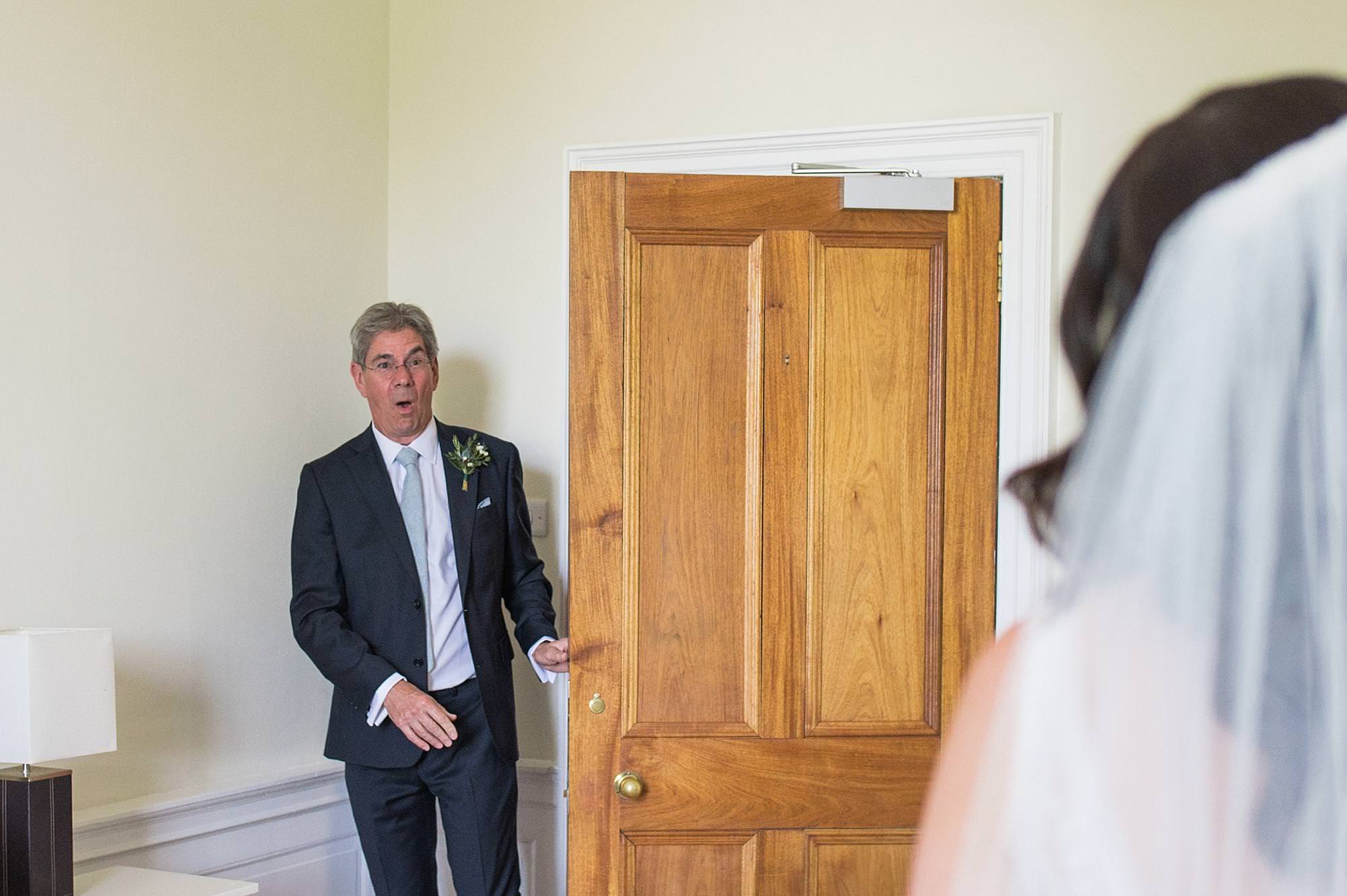 Man in dark suit gasps as he sees bride in wedding dress for first time